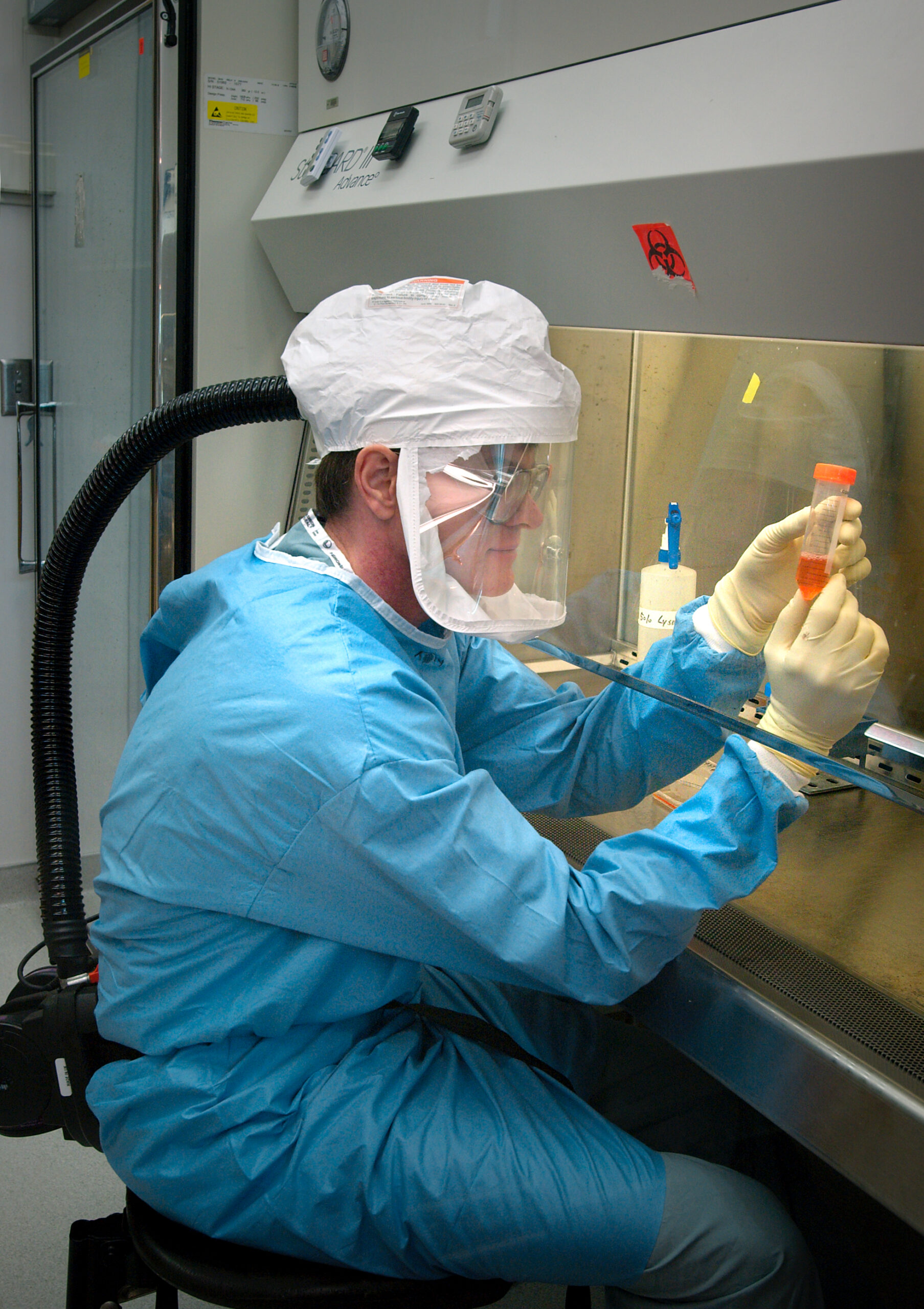 Ricercatore intento ad analizzare provette in ambiente protetto.